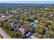 An aerial view of a community featuring lush greenery, a pool, tennis court, and residences with carports in the distance at 1901 Lennox E Rd # 1901, Palm Harbor, FL 34683