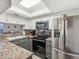 Kitchen featuring stainless steel appliances, gray cabinets, and a breakfast bar overlooking living area at 1901 Lennox E Rd # 1901, Palm Harbor, FL 34683