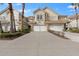 Tan two-story townhome with white double garage doors, landscaping, and palm trees at 14433 Mirabelle Vista Cir, Tampa, FL 33626