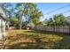 A large, sunny backyard features green grass and a wood fence at 523 Deville E Dr, Largo, FL 33771