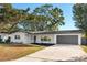 Charming single-story home with white brick, gray trim, well-maintained landscaping, and a gray two-car garage at 523 Deville E Dr, Largo, FL 33771
