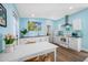 Charming kitchen with white cabinets, modern appliances, and a cozy dining area, enhanced by vibrant beach-themed art at 1925 Beach Se Dr, St Petersburg, FL 33705
