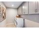 Bright laundry room with gray cabinets, washer, dryer, and tile floor at 31457 Woodland Race Loop, Wesley Chapel, FL 33545