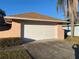 White garage door with peach-colored stucco walls and landscaping at 5105 Garden Vale Ave, Tampa, FL 33624