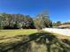 Expansive grassy backyard with mature trees and a white fence at 6823 Bottle Brush Dr, Port Richey, FL 34668