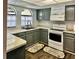 Charming kitchen features gray cabinets, marble countertops, stainless steel sink, arched windows, and wooden floors at 9107 Lingrove Rd, Weeki Wachee, FL 34613