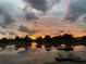 Serene lake view at sunset features colorful sky reflections and a charming dock with chairs at 9107 Lingrove Rd, Weeki Wachee, FL 34613