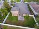 Aerial view of a fully fenced backyard with lush grass, a screened-in patio, and a decorative paved area at 11240 Ragsdale Ct, New Port Richey, FL 34654