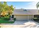 Tan two-car garage villa with gray roof, landscaping, and paved driveway at 3401 Avenida Madera # B, Bradenton, FL 34210