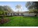 White brick ranch home with a large green lawn and mature palm trees at 15909 Amberly Dr, Tampa, FL 33647