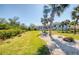 Picturesque backyard with manicured lawn, palm trees, a pond, and a white home in the background at 5951 Bay Dr, Gulfport, FL 33707