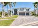 Beautiful two-story home featuring a manicured lawn, brick driveway, and lush palm trees at 5951 Bay Dr, Gulfport, FL 33707