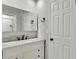 A bathroom provides an updated vanity with a light marble countertop, dark hardware, and a decorative mirror at 7801 17Th N Way, St Petersburg, FL 33702