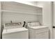 A tidy laundry room with washer, dryer, and overhead shelving at 7801 17Th N Way, St Petersburg, FL 33702