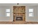 A living room with a stone fireplace and wood-look floors is brightened by two windows at 7801 17Th N Way, St Petersburg, FL 33702