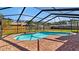 A kidney-shaped pool with brick surround sits in a screened-in enclosure against a wooden privacy fence and blue skies at 7801 17Th N Way, St Petersburg, FL 33702