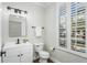 Modern powder room with white vanity, toilet, and large window with plantation shutters at 9540 W Park Village Dr, Tampa, FL 33626