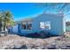 Side view of light blue home with a bright blue door, small palms, a one-car garage, and large window at 16006 2Nd E St, Redington Beach, FL 33708