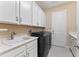 Laundry room with white cabinets, a utility sink and washer/dryer at 30280 Southernwood Ct, Wesley Chapel, FL 33543