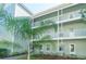 Two-story building with light green exterior, balconies, and landscaping at 330 Promenade Dr # 207, Dunedin, FL 34698