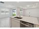 Clean kitchen island with sink and stainless steel dishwasher overlooking a living area and backyard access at 3952 Big Sky Dr, Spring Hill, FL 34604