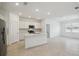 Bright, open kitchen with stainless appliances, white cabinets, island, and tile floors leading to the living area at 3952 Big Sky Dr, Spring Hill, FL 34604