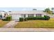 Charming single-story home featuring a well-manicured front yard with lush green hedges and a white tile roof at 9201 40Th N Way, Pinellas Park, FL 33782