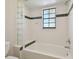Bathroom with white tiled walls, tub and glass block feature at 11114 Lake Sassa Dr, Thonotosassa, FL 33592