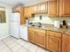 Galley kitchen with wood cabinets, granite counters, and white appliances at 1515 Pinellas Bayway S # 40, St Petersburg, FL 33715