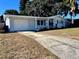 Charming single-story home with a white exterior, attached garage, and driveway at 3649 Bradford Dr, Holiday, FL 34691