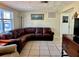 Living room with a large brown sectional sofa, tiled floors, and several windows at 3649 Bradford Dr, Holiday, FL 34691