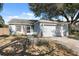 One-story house with a two-car garage and a tree-lined front yard at 11117 Bloomington Dr, Tampa, FL 33635