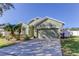 Green house exterior, two-car garage, and palm trees at 11341 Flora Springs Dr, Riverview, FL 33579