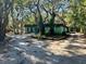 Light green house with a brown roof, surrounded by mature trees and a gravel driveway at 12308 N 52Nd St, Temple Terrace, FL 33617