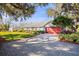 Ranch style home with red garage door and mature trees at 3111 Lewis Rd, Dover, FL 33527