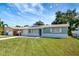 Newly renovated home with a light blue exterior, white accents, and a well-manicured lawn at 8411 7Th N St, St Petersburg, FL 33702