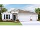One-story home with a three-car garage, stone accents, and a landscaped lawn at 10725 Tippecanoe Pl, Parrish, FL 34219