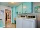 Laundry room with teal cabinets, washer, dryer, and kitchen view at 8408 Monarch Cir, Seminole, FL 33772