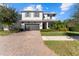 Two-story home with gray siding, dark garage door, and a brick paver driveway at 12107 Rustic River Way, Tampa, FL 33635