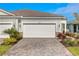 Home exterior featuring a well-manicured lawn, a brick driveway, and a two-car garage at 18475 Green Garden Ct, Venice, FL 34293