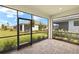 Screened patio with brick flooring, showcasing serene views of the manicured lawn, neighboring home, and lush foliage at 18475 Green Garden Ct, Venice, FL 34293