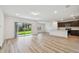 Open living space featuring hardwood floors, white walls, and kitchen access with stainless appliances at 10524 Hidden Banks Gln, Parrish, FL 34219