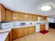 View of kitchen with wood cabinets, white appliances, and laminate flooring at 162 S Saint Thomas Cir, Apollo Beach, FL 33572