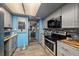 Modern kitchen with gray cabinets, blue accent wall, and stainless steel appliances at 785 S Village N Dr # 202, St Petersburg, FL 33716