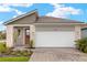 Charming single-story home featuring a brick driveway, stone accents, and a bright orange front door at 12170 Meditation Trl, Venice, FL 34293