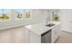 Kitchen island includes a stainless sink, dishwasher, and bar seating area at 12170 Meditation Trl, Venice, FL 34293