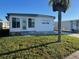 White single-wide manufactured home with a small lawn and palm tree at 13225 101St St # 451, Largo, FL 33773