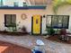 A vibrant yellow front door framed by lush landscaping and a brick walkway, enhancing the home's welcoming appeal at 14016 Marguerite Dr, Madeira Beach, FL 33708