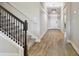 Inviting hallway with wood-look tile flooring, stairway with dark wood railing, and modern lighting fixture at 21291 Snowy Orchid Ter, Land O Lakes, FL 34637