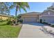 Front view of a two-car garage villa with a palm tree and driveway at 2410 Nottingham Greens Dr, Sun City Center, FL 33573